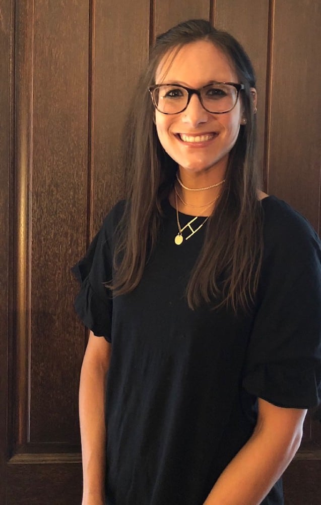 A woman wearing glasses and smiling for the camera.